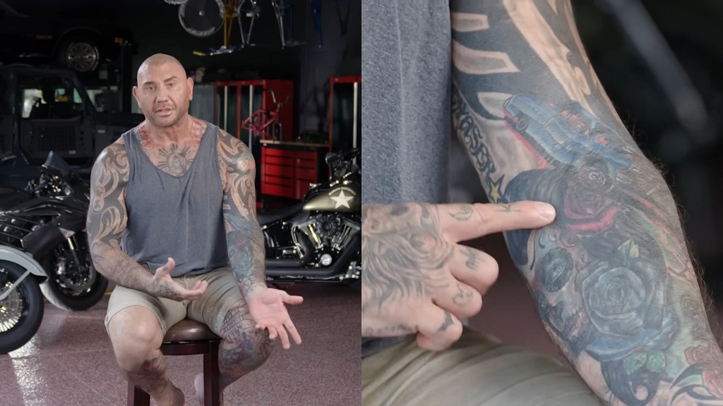 Dave Bautista points to a forearm tattoo during an interview about a tattoo he covered