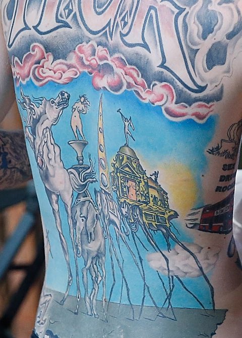 Archival close view of Machine Gun Kelly's colorful Salvador Dalí-inspired backpiece, with surrealist figures and architecture