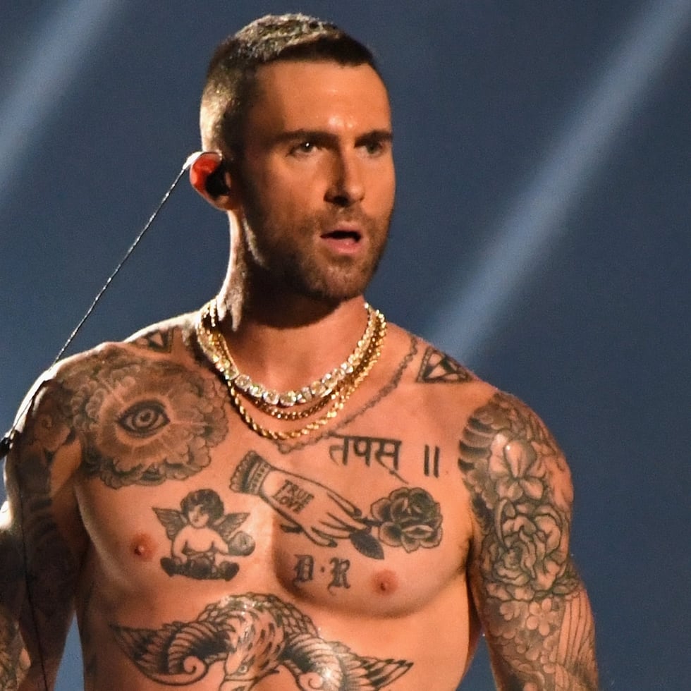 Adam Levine shirtless with a broad view of tattoos across his chest and arms