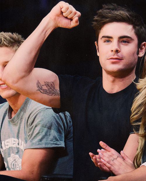 Zac Efron displaying the feather tattoo on his inner right bicep