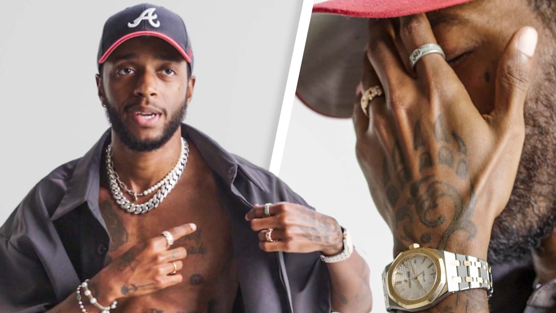 GQ tattoo-tour image of 6LACK pointing to the cursive self-made tattoo on his chest, with a close view of hand tattoos