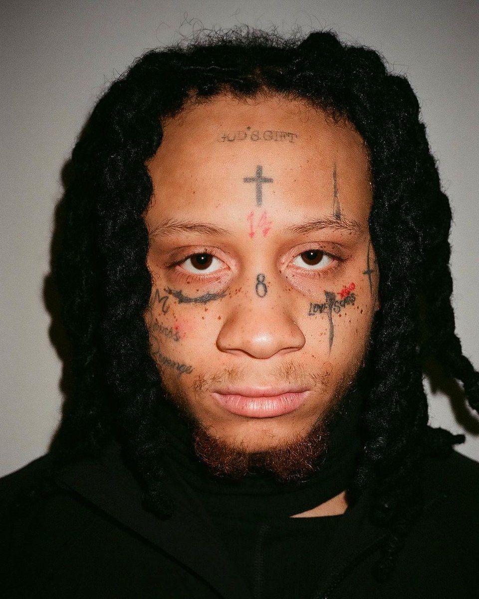Trippie Redd tattoos: close portrait showing the crosses, numbers and script around the face
