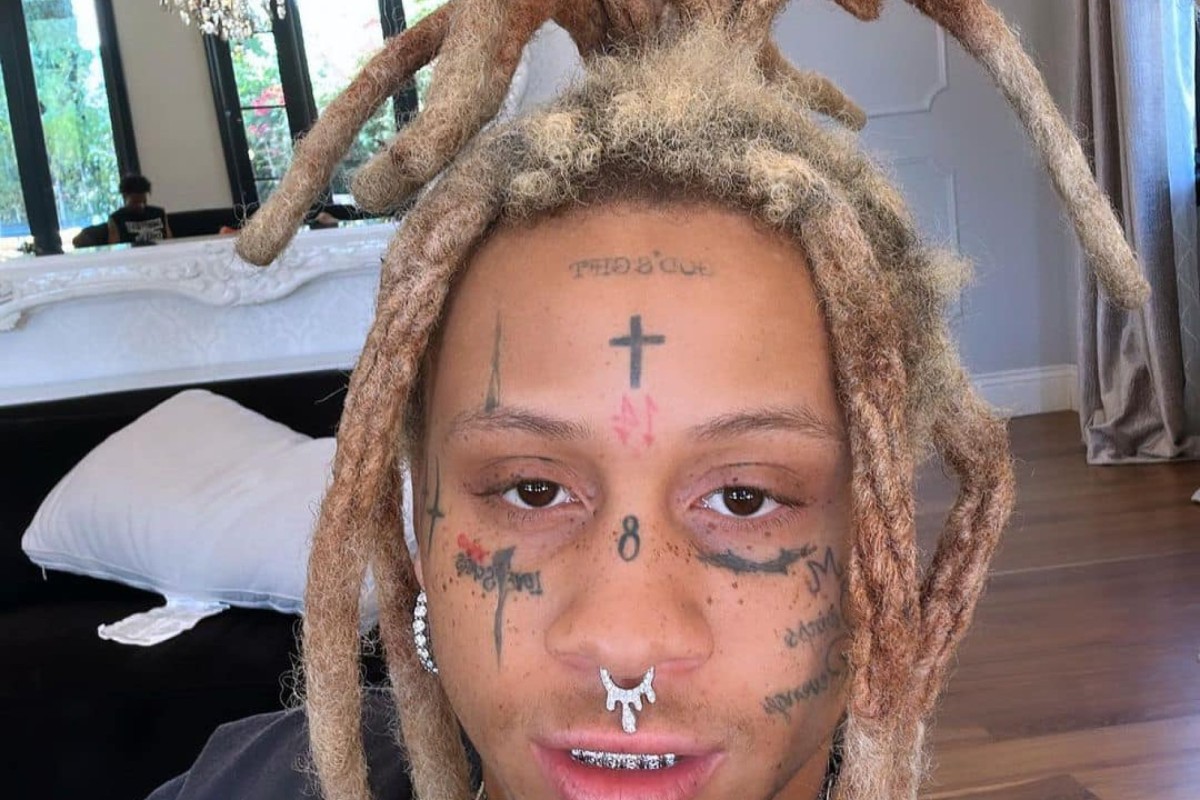 Trippie Redd tattoos: different indoor portrait showing the forehead cross, nose number and neck ink
