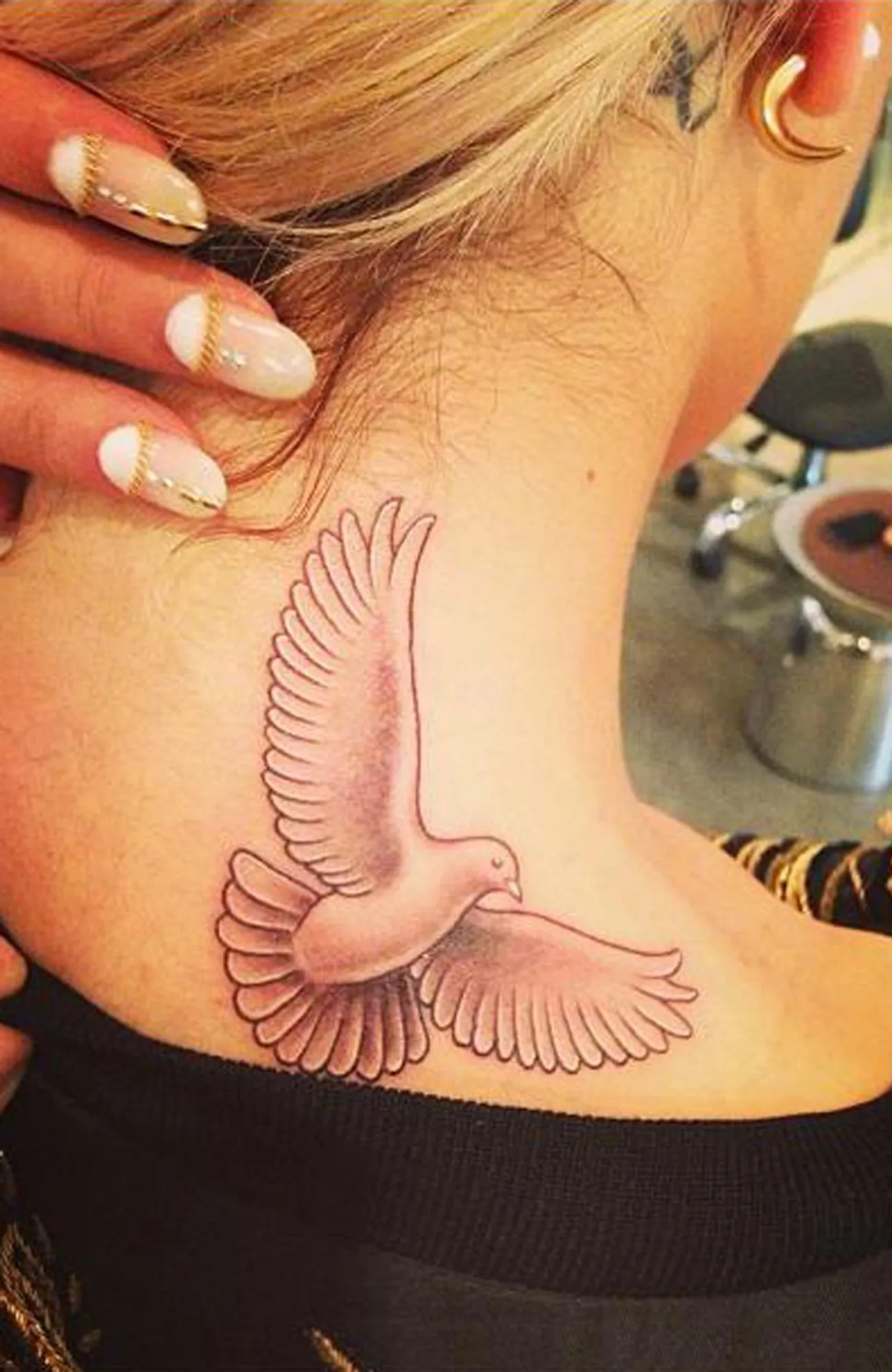 Rita Ora tattoos: studio photograph showing the dove tattoo on the back of the neck