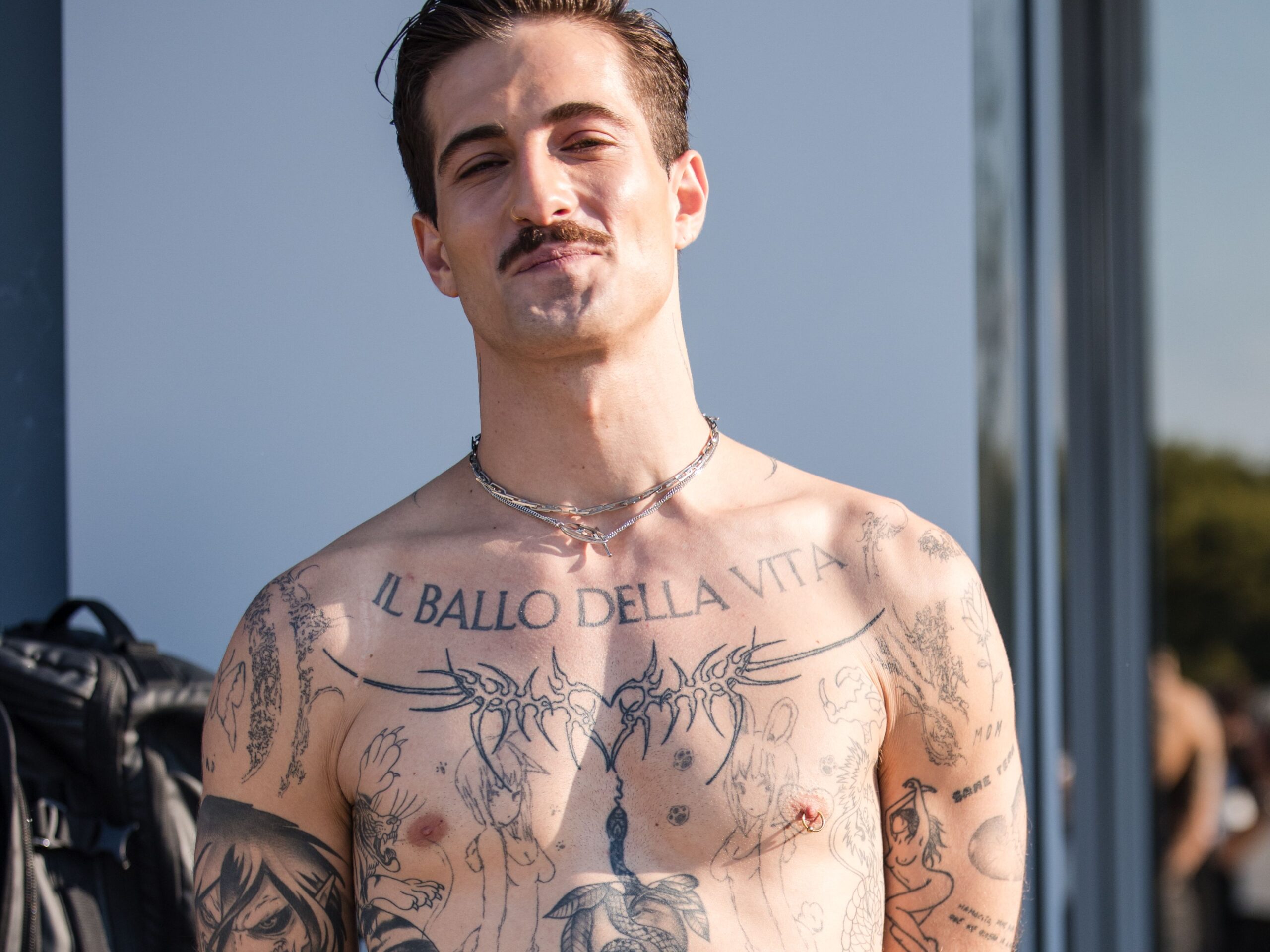 Damiano David tattoos: Large Il ballo della vita lettering across the upper chest