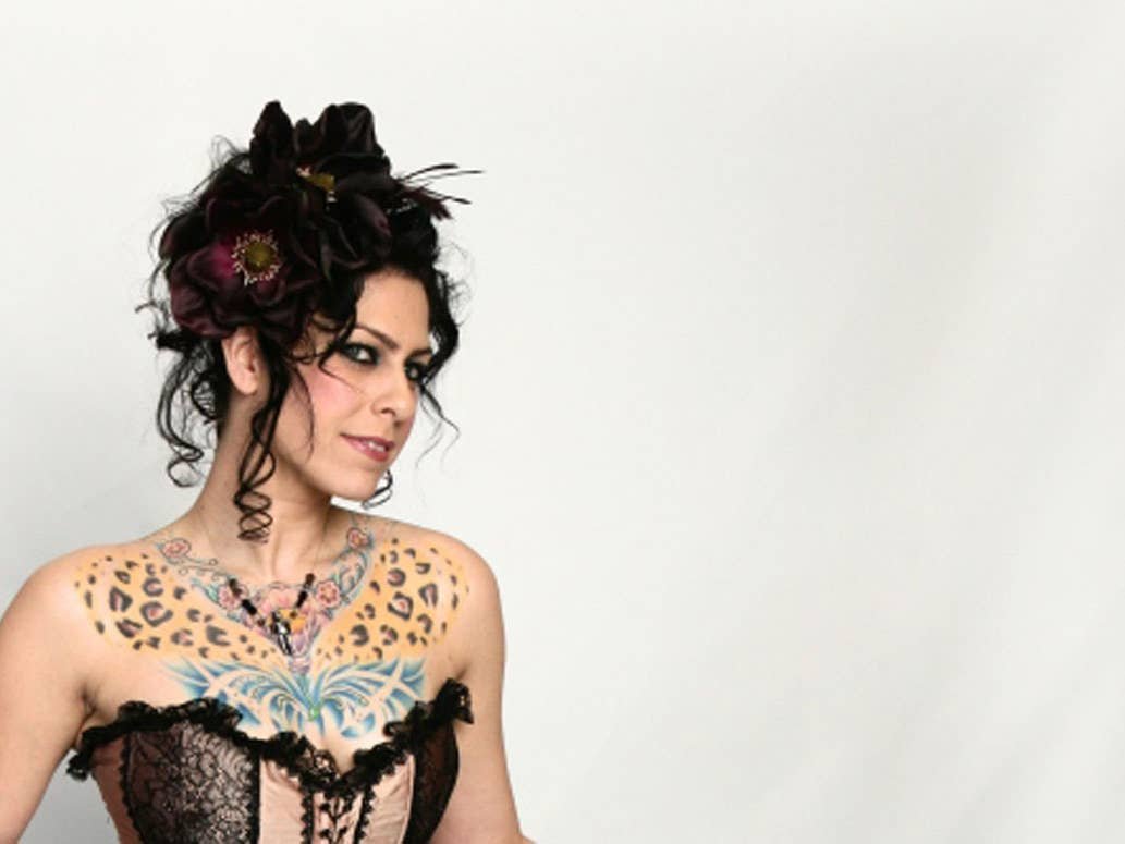 Danielle Colby showing leopard and butterfly chest tattoos