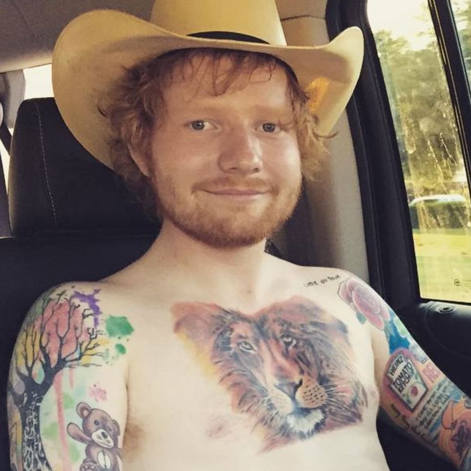 Ed Sheeran showing the colorful lion chest tattoo and surrounding sleeve tattoos