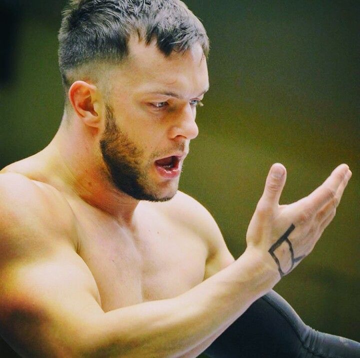 Finn Bálor inspecting the tattoos on his hand