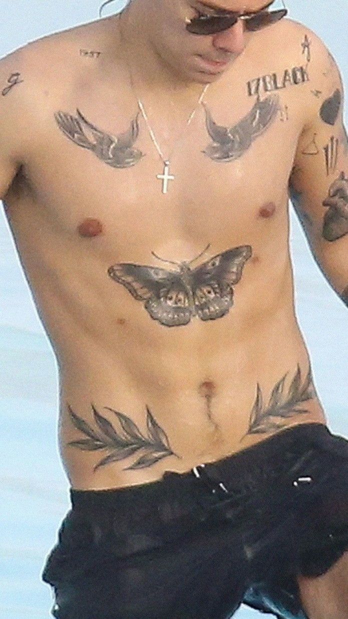 Harry Styles showing his butterfly and swallow tattoos