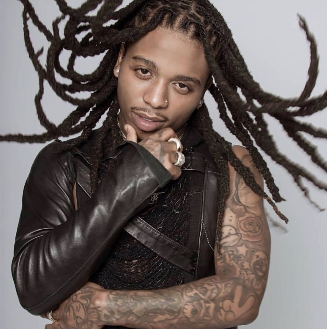 Jacquees showing multiple arm tattoos including lettering and traditional designs