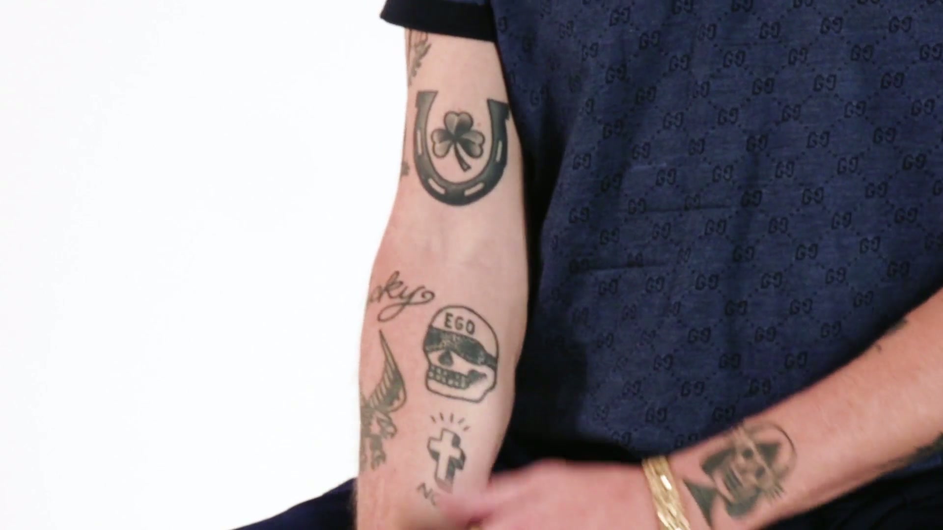 Macklemore EGO skull and cross forearm tattoos
